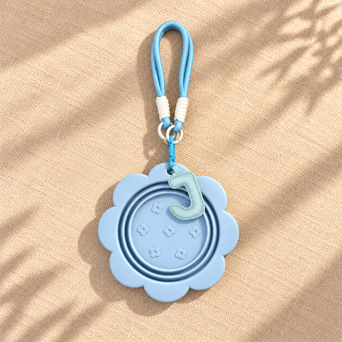 Folded sky blue pet travel bowl with matching blue hook and lanyard